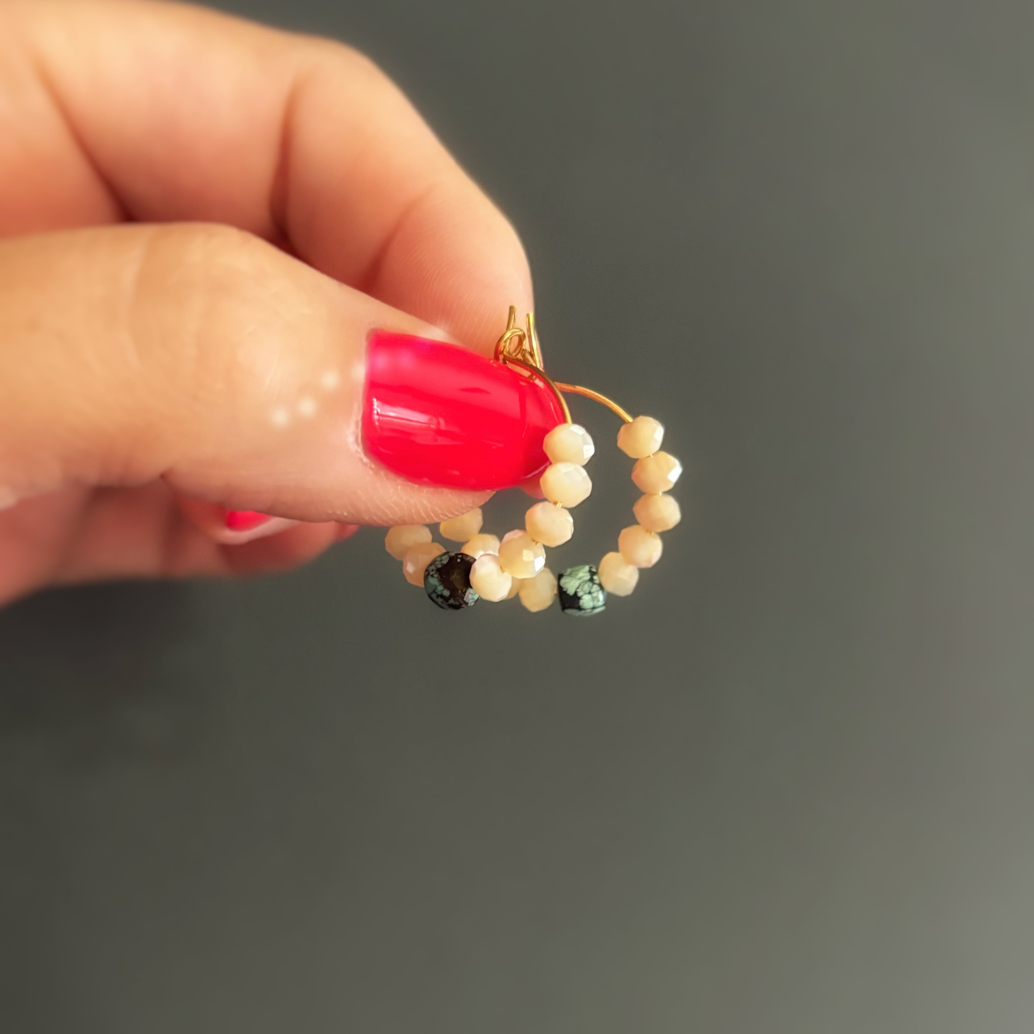 Détail d'une créole Signature tenue à la main, perles de nacre et turquoise naturelle