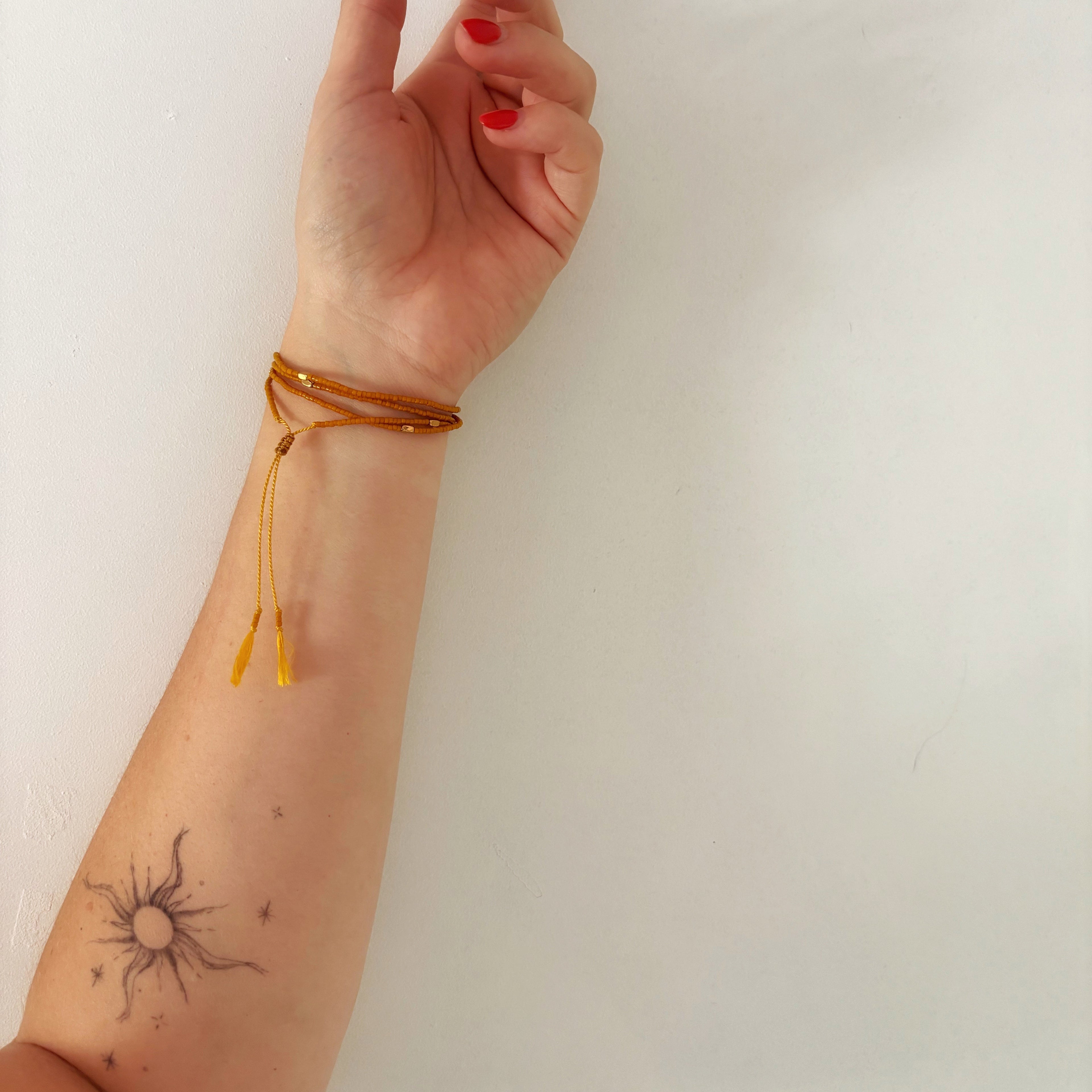 Tatouage soleil et bracelet ocre