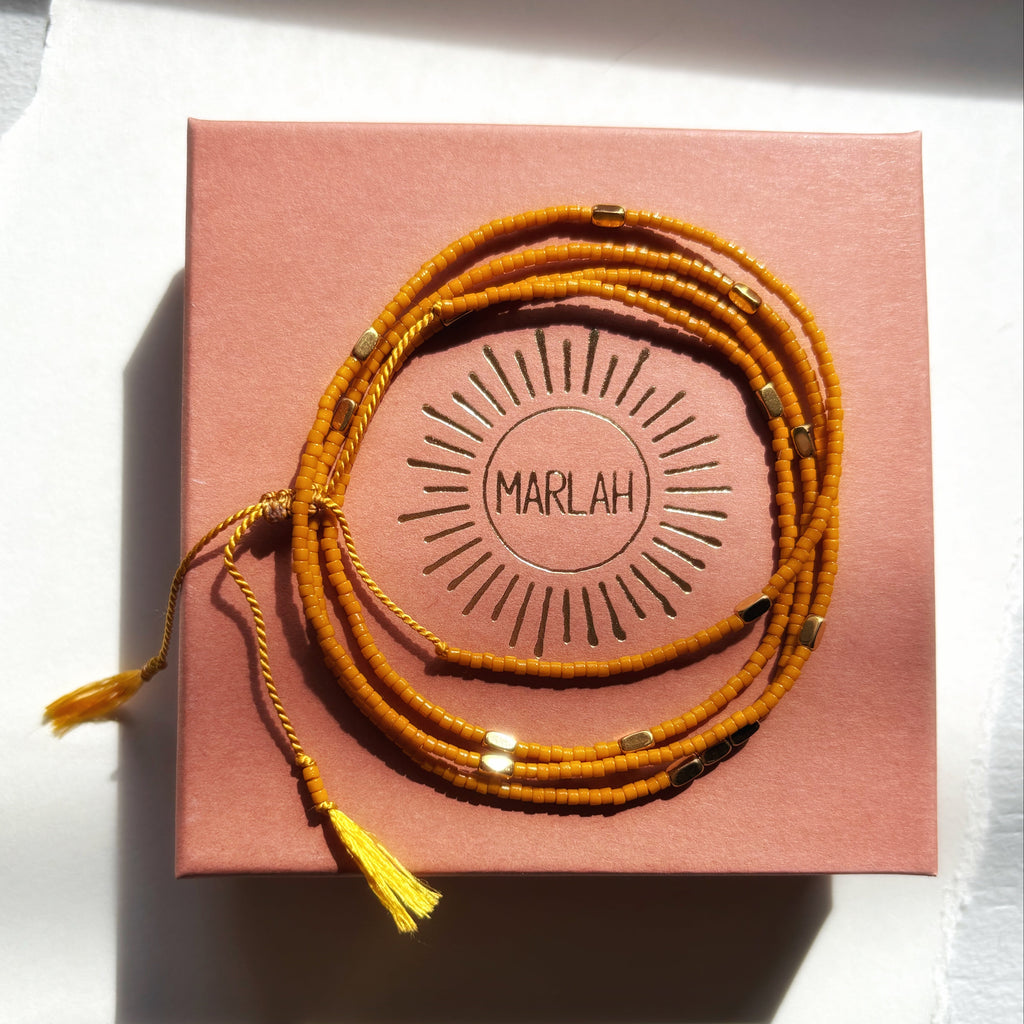Bracelet wrap miyuki ocre Marlah posé sur sa boite packaging de LUXE