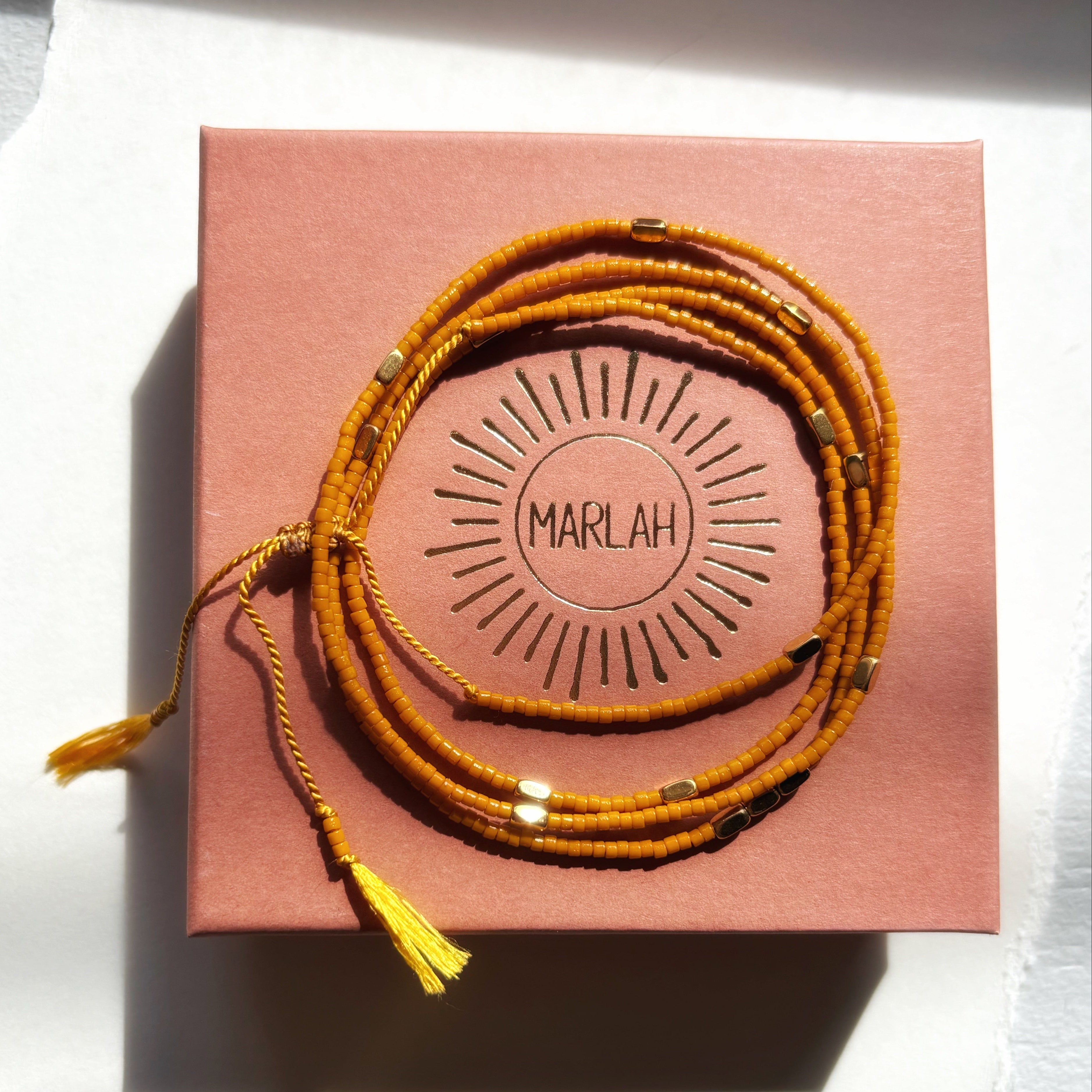 Bracelet wrap miyuki ocre Marlah posé sur sa boite packaging de LUXE