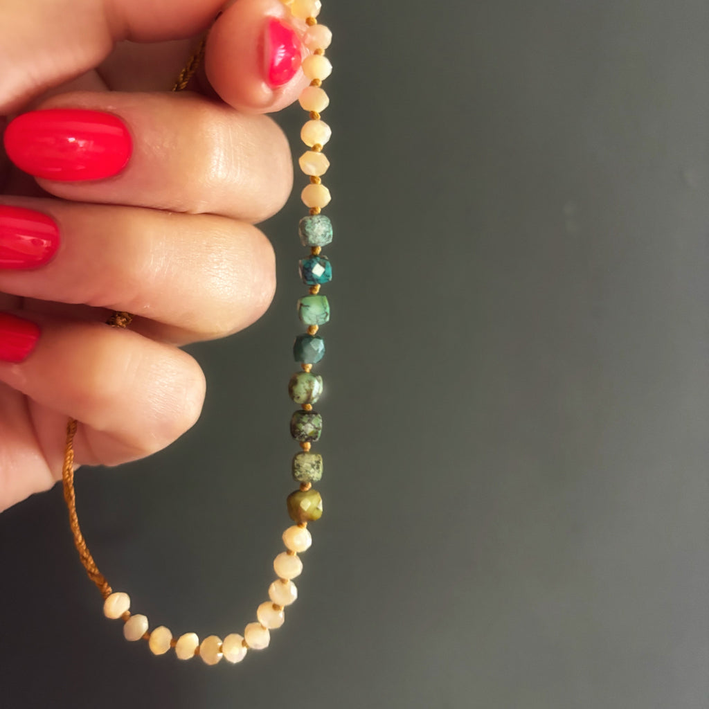 Détail du bracelet Signature tenu à la main, perles de nacre et turquoise naturelle