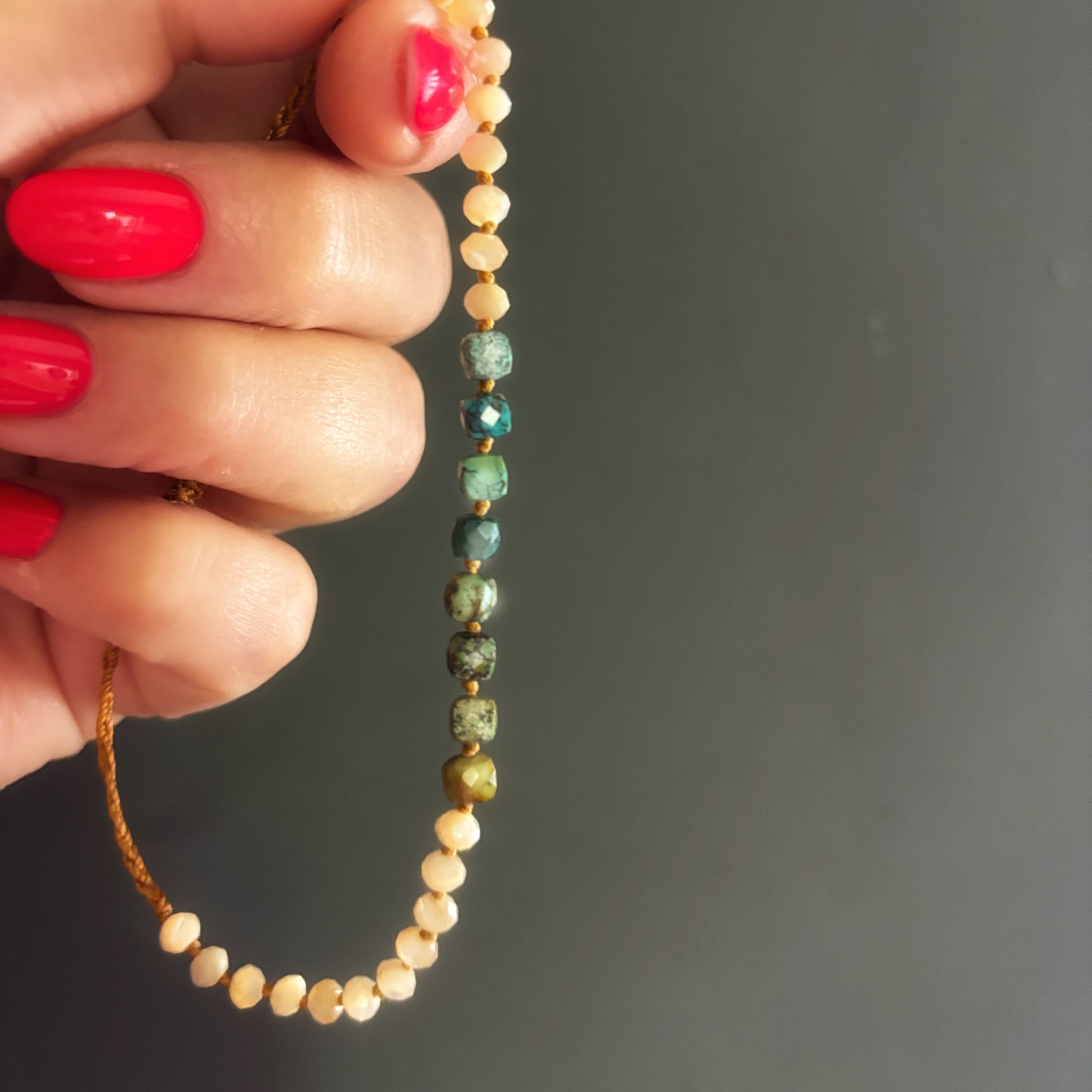 Détail du bracelet Signature tenu à la main, perles de nacre et turquoise naturelle