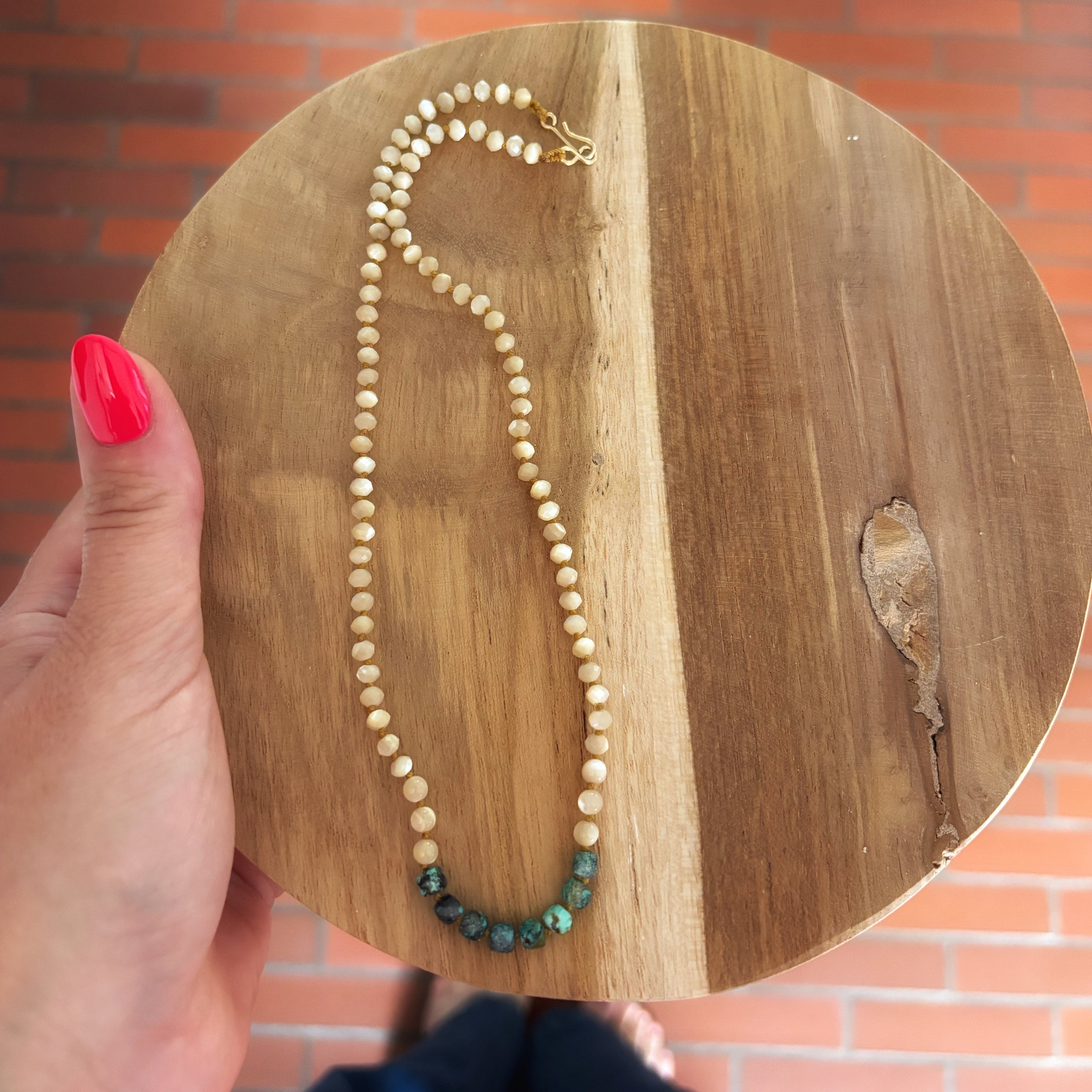 collier nacre et turquoise posé sur un plateau rond en bois