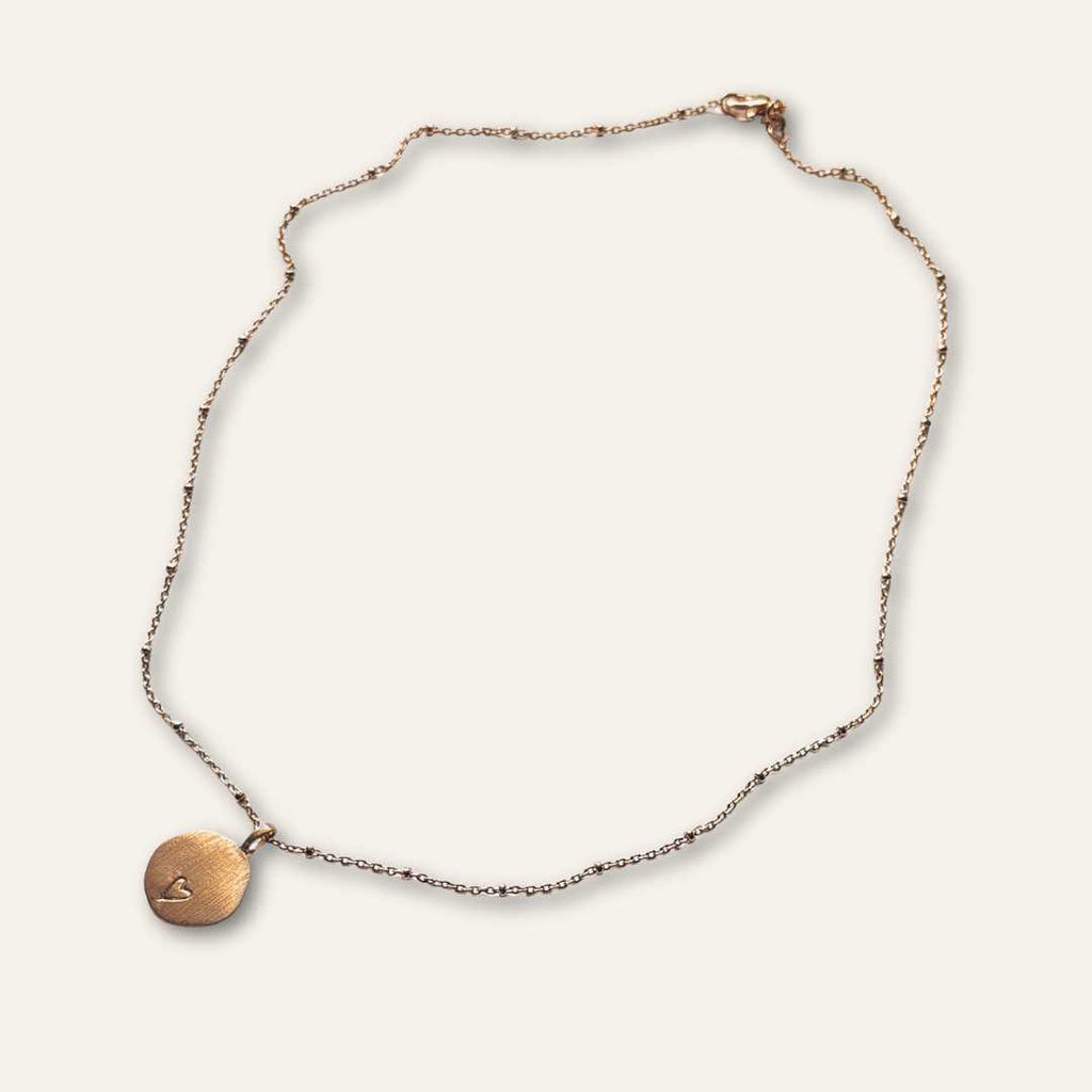 Collier porte bonheur en plaqué or à porter comme un talisman avec un petit coeur gravé à la main