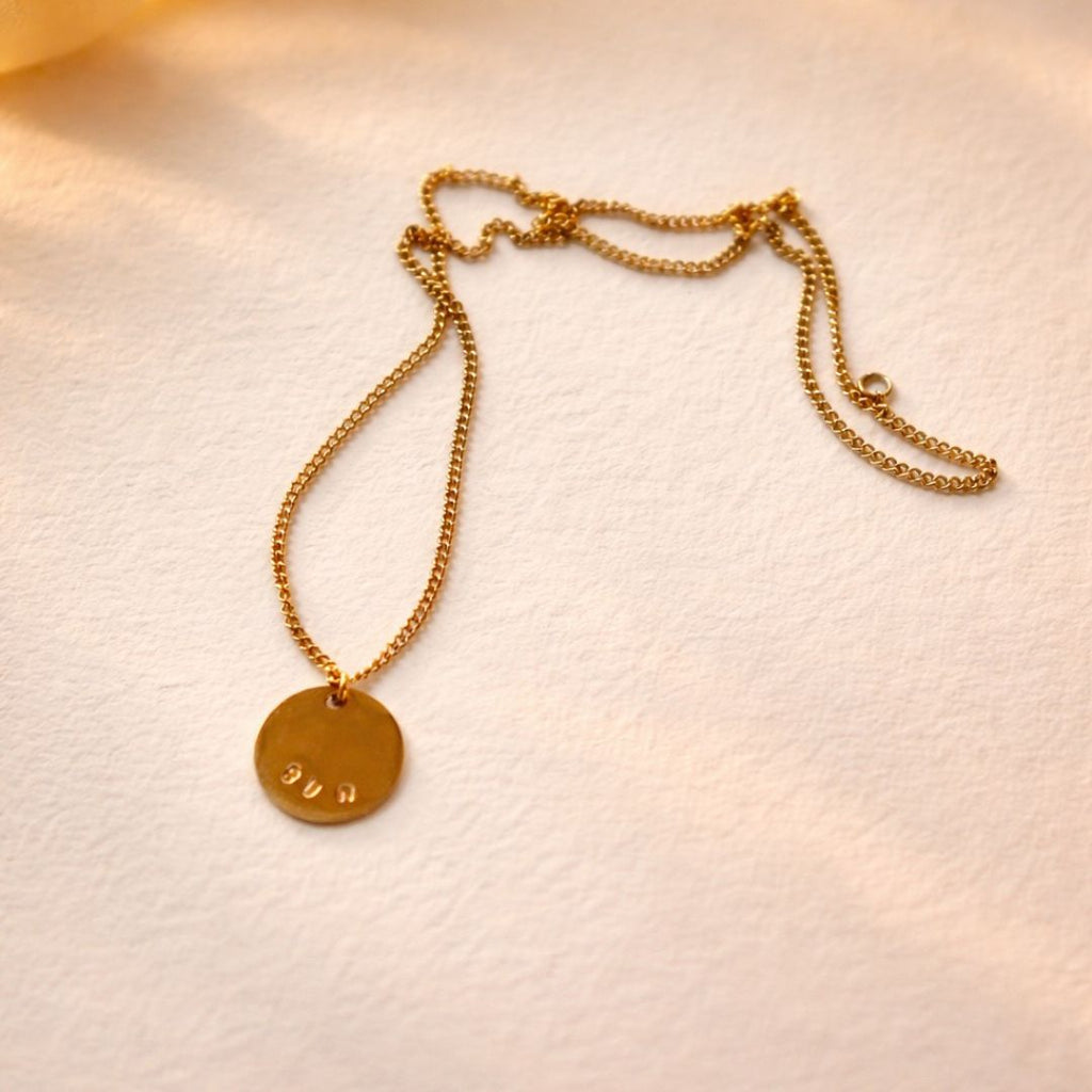 Gros plan sur le collier doré avec un message gravé à la main en Belgique