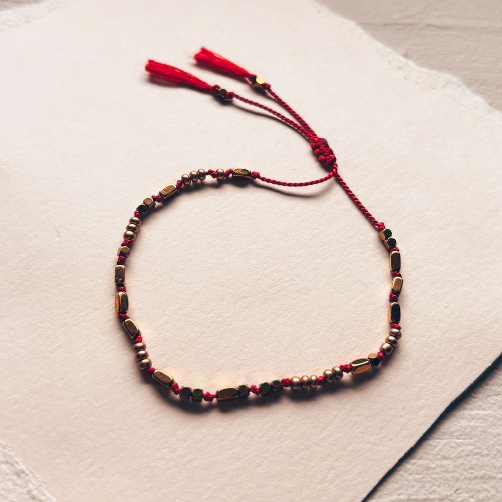 Détail du bracelet fil rouge en soie naturelle et perles dorées fait main MARLAH