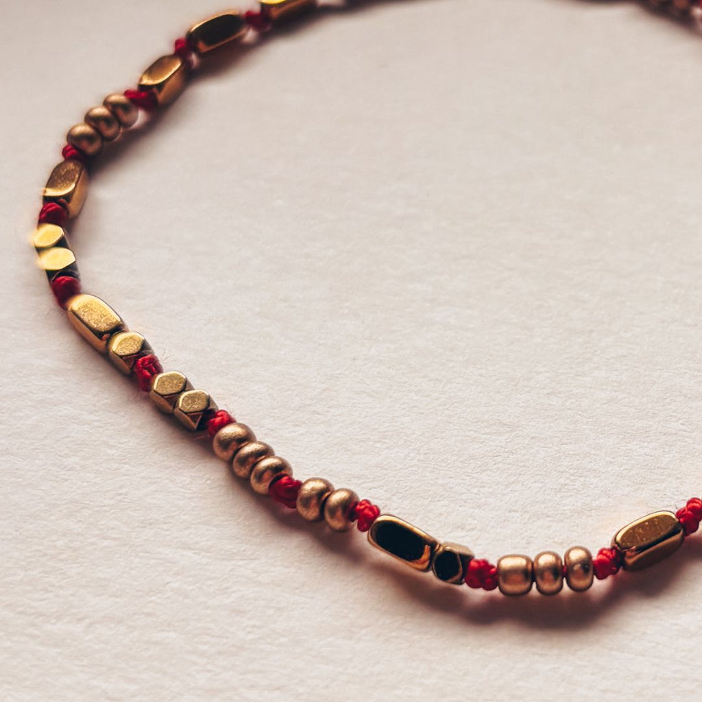Détail du bracelet fil rouge en soie naturelle et perles dorées fait main MARLAH