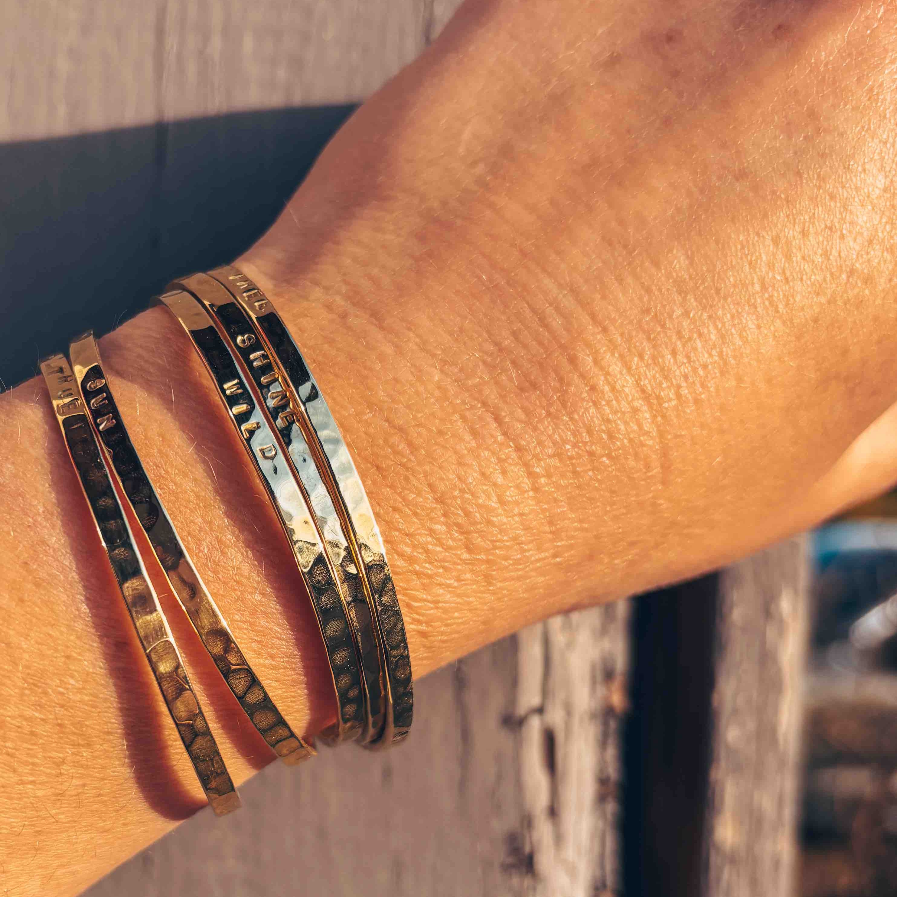 Accumulation de bracelets fins dorée par une créatrice belge