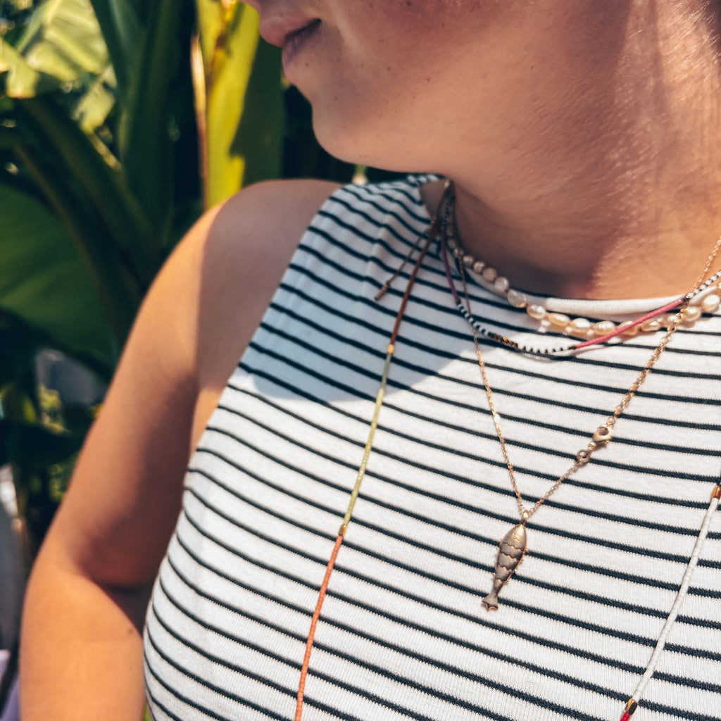 Collier surfeur HIPPY porté en ambiance tropicale - bijou festival bohème Ibiza