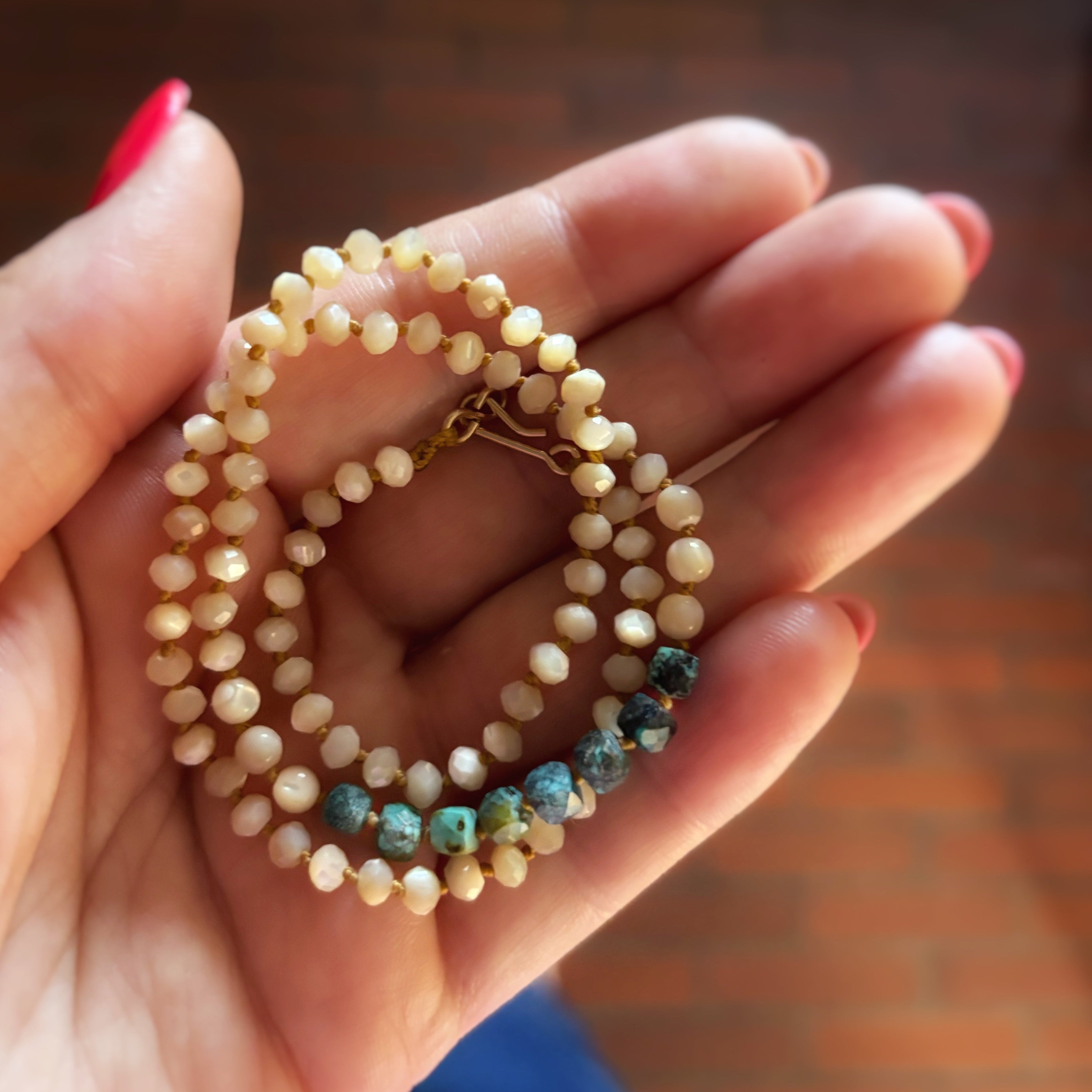 Collier Signature nacre et turquoise naturelle enroulé dans la main