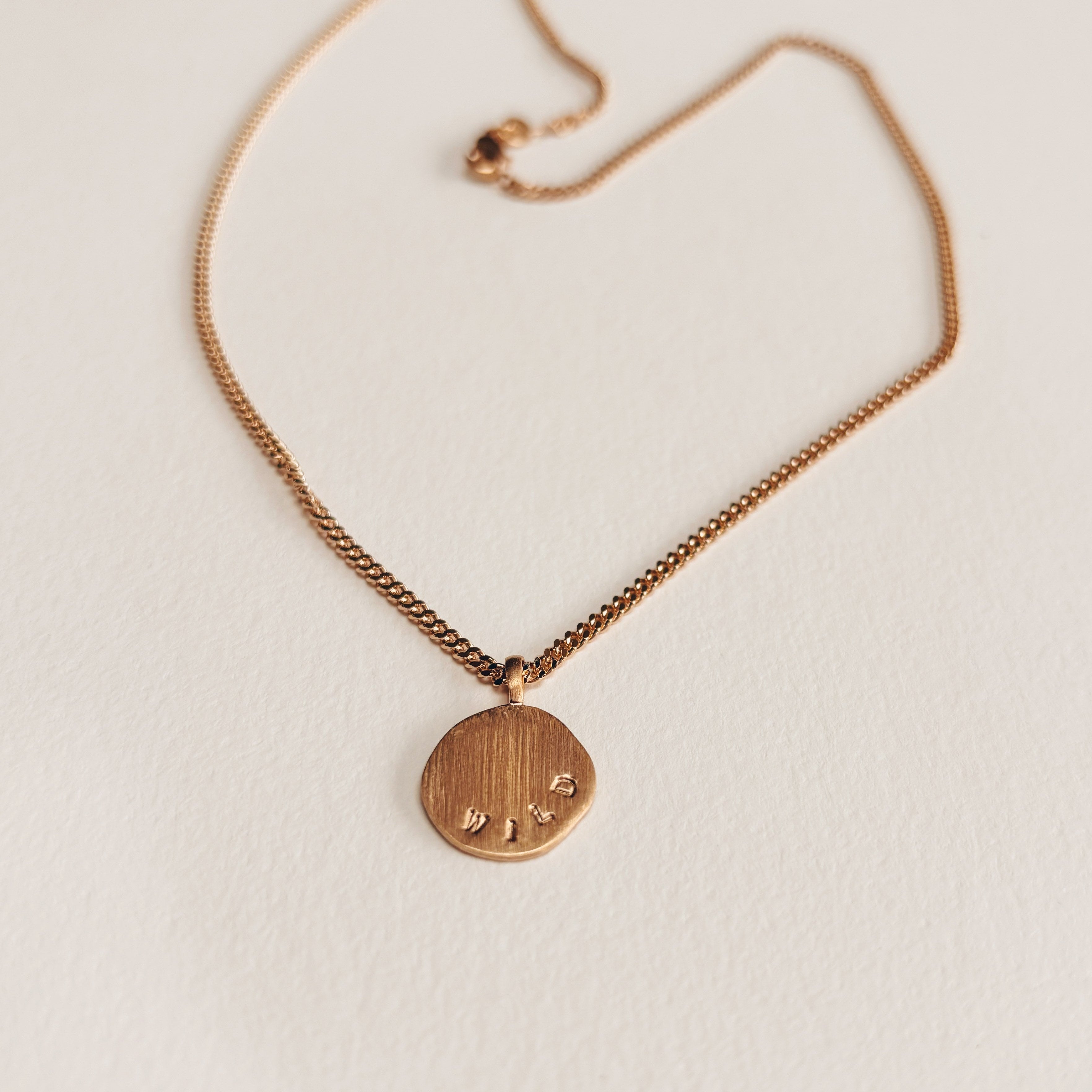 Gros plan sur pendentif poiçonné à la main message wild